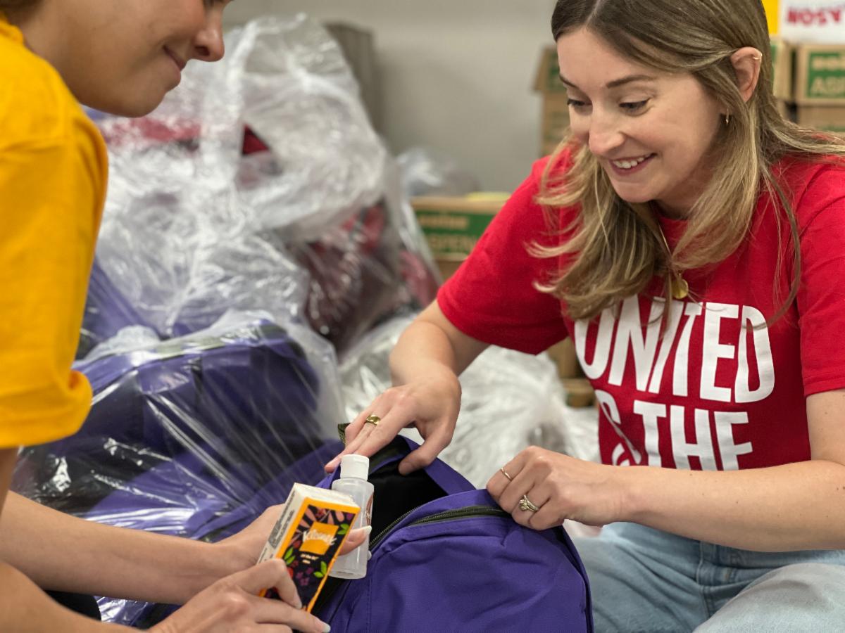 United Way employees stuff a backpack with cleaning products