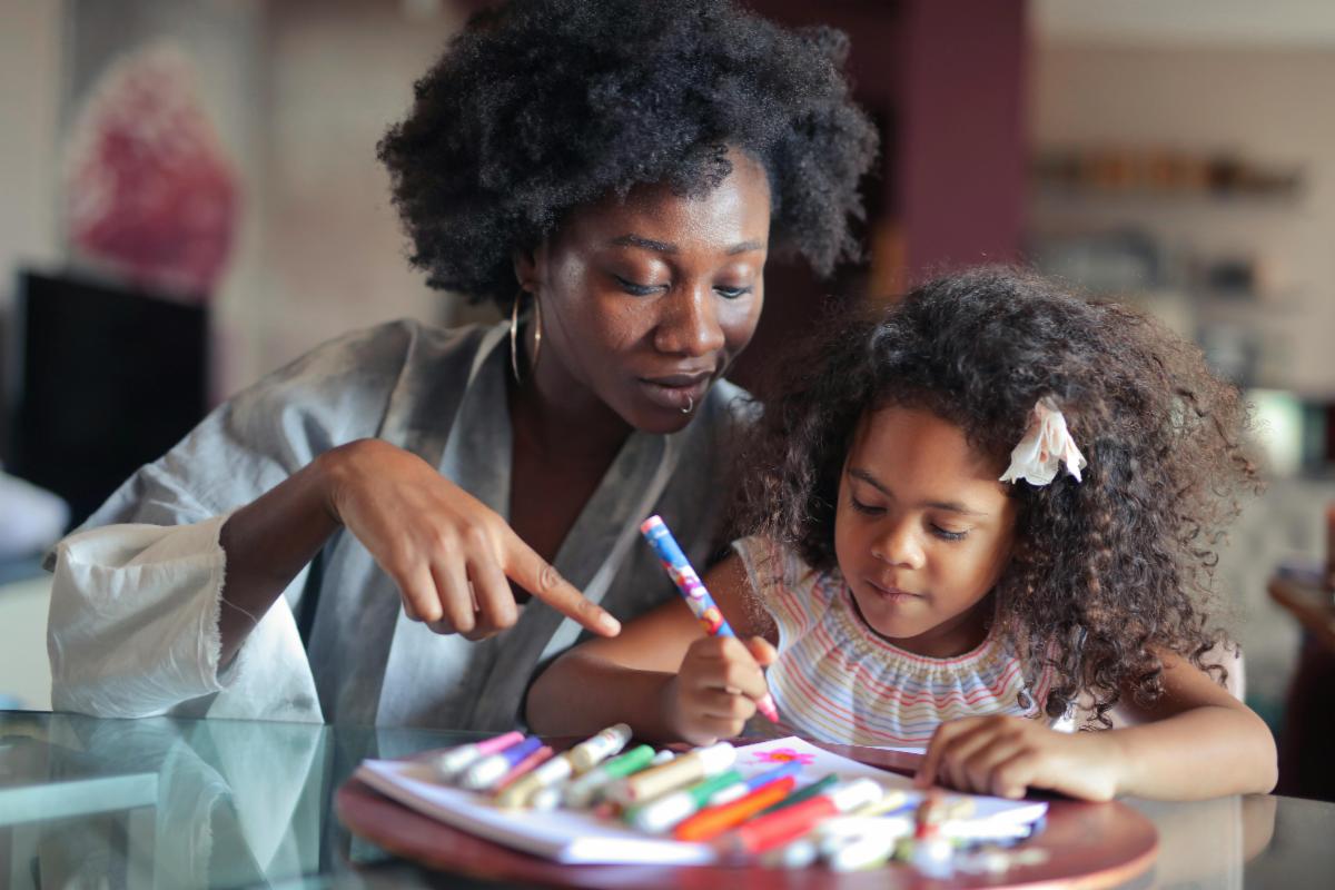 A caregiver helps a child draw