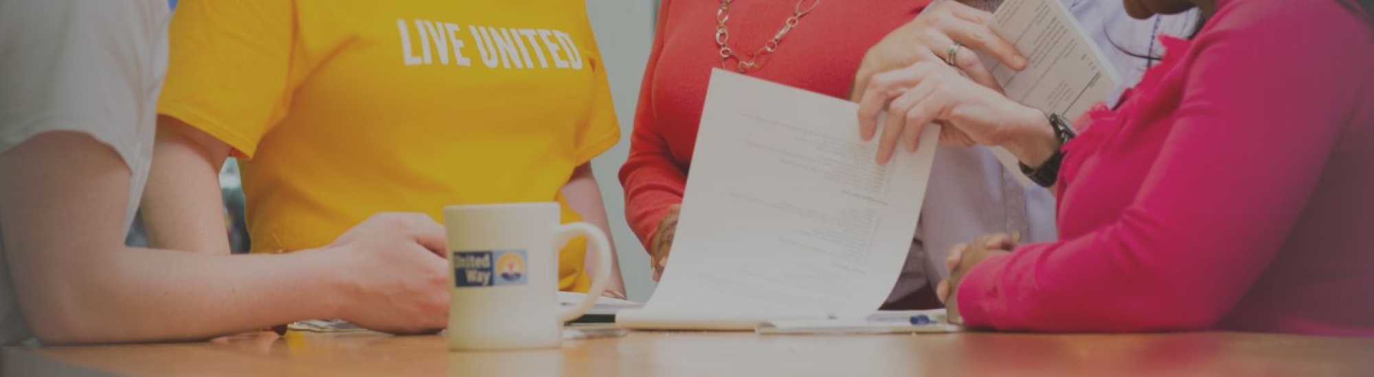 Group of people standing around a table and looking at paperwork 