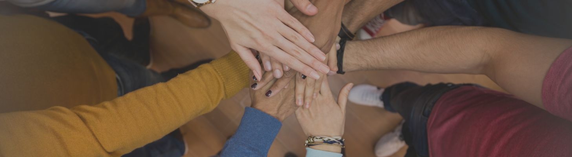 Several people with their hands piled on top of another 